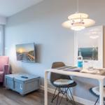 Living area with dining table, chairs, TV, and window.