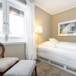 Schlafzimmer mit Bett, Stuhl, Fenster und Wandbild.