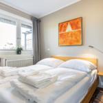 Schlafzimmer mit Bett, Fenster und Wandbild.