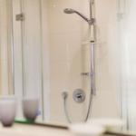 Dusche mit Glaswand und Duschbrause in weißer Wand