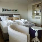 Zimmer mit Doppelbett, Sessel und Sideboard mit Regal