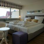Schlafzimmer mit Bett, Sessel und Fensterblick
