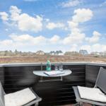 Terrasse mit Tisch und zwei Stühlen, Blick auf Feld und Häuser