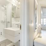 Badezimmer mit Dusche, Waschbecken und Spiegel. Blick in angrenzenden Raum.