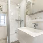 Badezimmer mit Dusche, Waschbecken und Fenster.