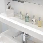 Badezimmer mit Waschbecken, Wasserhahn und Pflegeprodukten auf der Ablagefläche.
