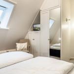 Schlafzimmer mit Dachfenster, Bett, Kleiderschrank und Fernseher.