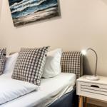 Schlafzimmer mit Bett, Kissen und Nachttisch mit Lampe.
