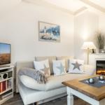Wohnzimmer mit Sofa, Fernseher und Kaminofen.
