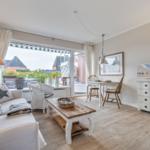 Living room with sofa, dining table, and TV cabinet. Balcony with seating area.