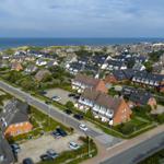 Aerial view of coastal village with houses and sea in background.