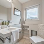 Bathroom with sink, mirror, toilet, and window