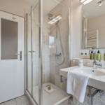 Shower area with shower cabin, sink, and mirror
