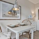 Dining room with table, chairs, and wall art of sailboats.