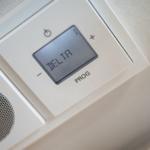 Digital thermostat with display and control buttons.