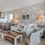 Living and kitchen area with sofa, chair, and kitchen cabinets.