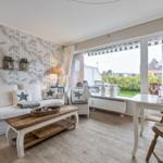 Living and dining area with sofa, table, and view of balcony.