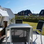 Terrace with table, chairs, and beach chair. View of lawn and houses.