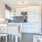 Kitchen with dining area, white built-in kitchen, and table with chairs.