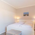 Bedroom with white bed, two nightstands, and wall picture.