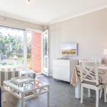 Living and dining area with table, chairs, and view to balcony.