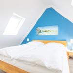 Schlafzimmer mit Dachschräge, blauer Wand, Holzbett und Dachfenster.