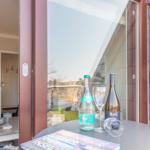Tisch mit Wein und Wasser vor Terrassentür. Küche und Flur im Hintergrund.