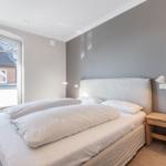 Bedroom with double bed, wooden side table, and window to balcony.