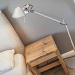 Bedroom with bed, wooden nightstand, and floor lamp.