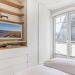 Bedroom with TV, bookshelf, and window view of roof