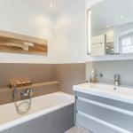 Bathroom with bathtub, sink, and mirror.