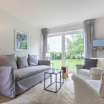 Living room with sofa, armchairs, and view of green area.