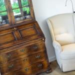 Antique cabinet and cream-colored armchair in room