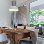 Dining room with wooden table, bench, and garden view.