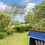 Garden with view of water and trees. Blue beach chair next to brick wall.