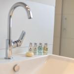 Sink with modern faucet and four bottles of toiletries.