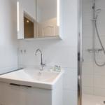 Bathroom with shower, sink, and lit mirror.