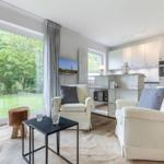 Living area with seating, kitchenette, and view of a garden.