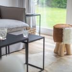 A gray sofa with table and stool by window