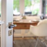 Door handle leads to dining room with wooden table and chairs.