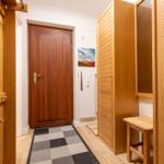 Entrance area with wooden doors, coat hooks, and tiled floor.