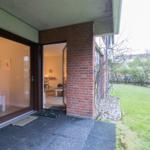 Entrance with glass doors leading to living area. Outdoor space with lawn and stone wall.
