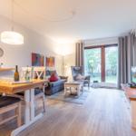 Living and dining area with wooden floor, sofa, dining table, and garden view.