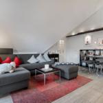 Wohn- und Essbereich mit Sofa, Tisch und Stühlen unter Dachschrägen.