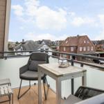 Balkon mit Tisch und Stühlen, Blick auf Wohnhäuser und Straße.