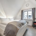 Schlafzimmer mit Doppelbett, Fenster und Sessel.