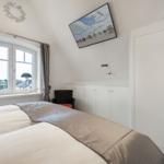 Schlafzimmer mit Bett, Fenster und Kleiderschrank. Wandbild zeigt Strand.