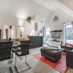 Wohn- und Essbereich mit grauer Couch, rotem Teppich und Essplatz unter hohem Dach.
