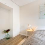 Schlafzimmer mit Bett, Nachttisch, Kleiderschrank und Wandbild.
