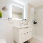 Badezimmer mit Dusche, Waschbecken und Spiegel